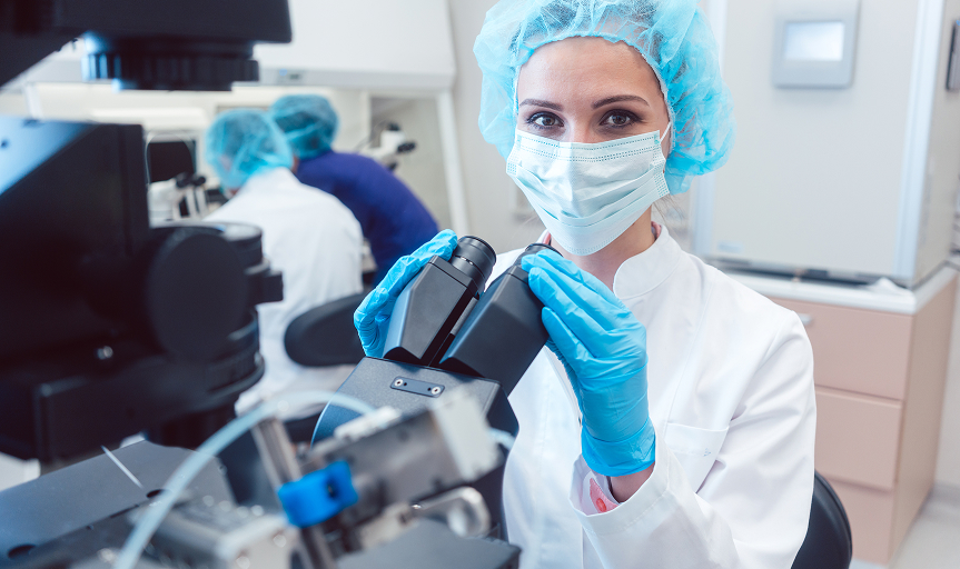Woman doctor working on manipulator fertilizing human eggs in fertility clinic lab